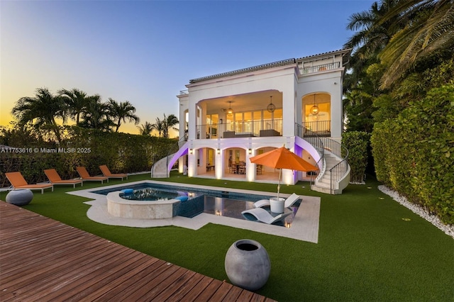 back of property at dusk with a patio area, stairway, and a lawn