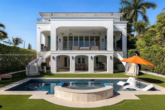 rear view of house with stairway, a lawn, stucco siding, a balcony, and a patio