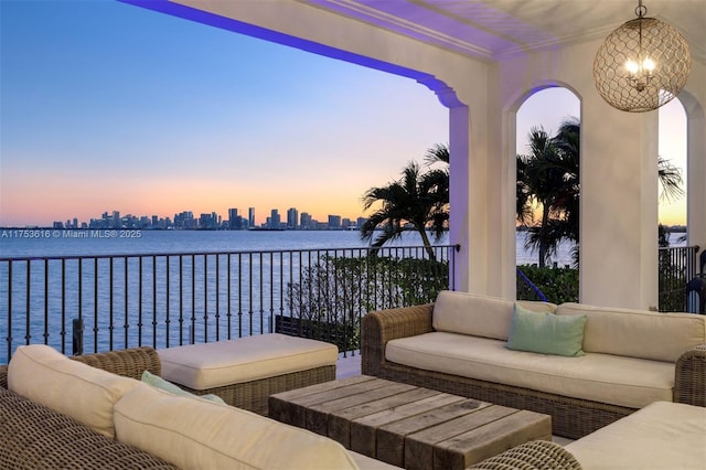 patio terrace at dusk featuring an outdoor living space, a water view, and a view of city