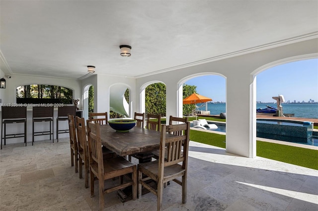 view of patio featuring outdoor dry bar, outdoor dining space, an outdoor pool, and a water view