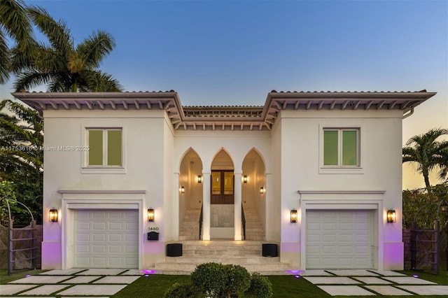 mediterranean / spanish-style home with fence, an attached garage, stucco siding, concrete driveway, and french doors