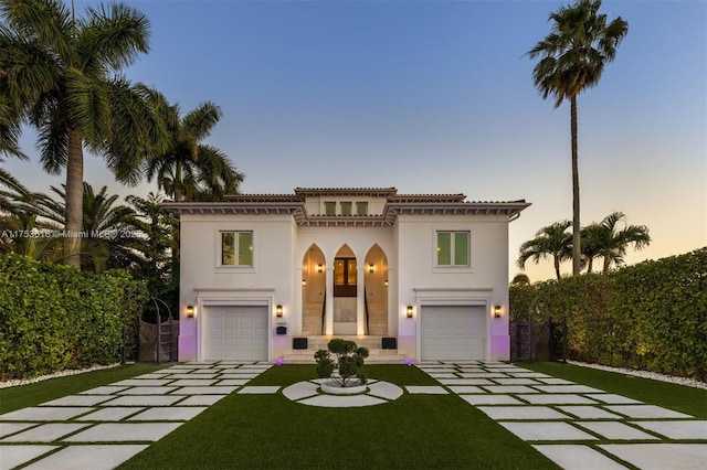 mediterranean / spanish home featuring a garage, a lawn, concrete driveway, and stucco siding