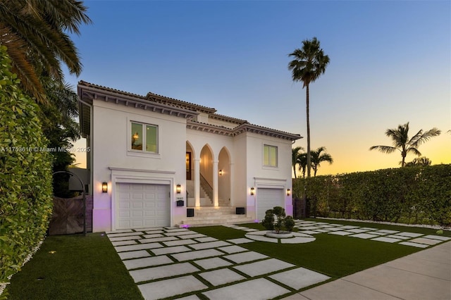 mediterranean / spanish home featuring stucco siding, an attached garage, and concrete driveway