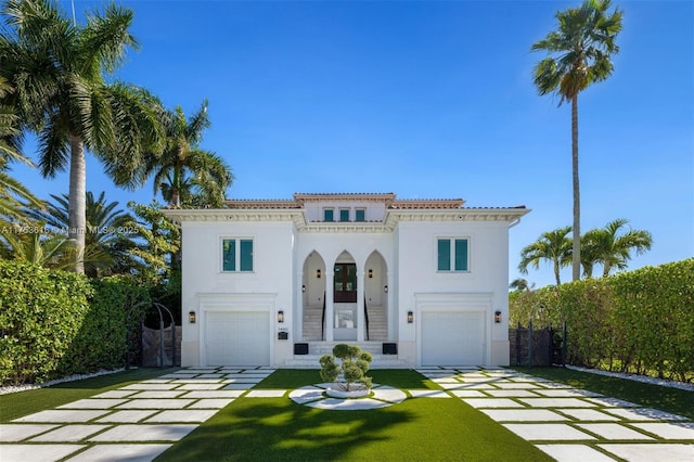 mediterranean / spanish-style home featuring a front yard, driveway, stucco siding, a garage, and a tile roof