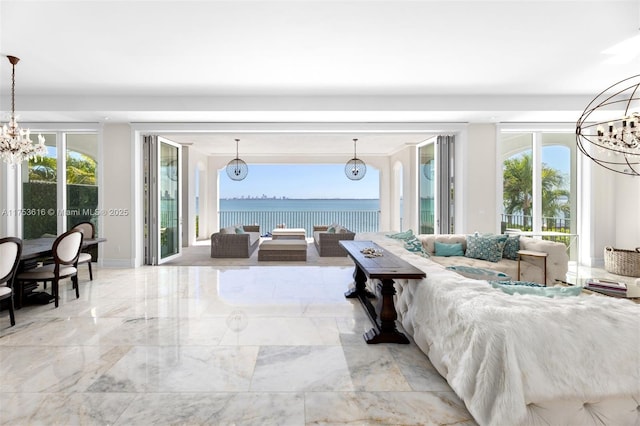 living area featuring a water view, a notable chandelier, and marble finish floor