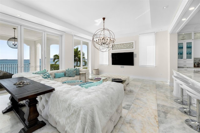 living room with recessed lighting, baseboards, an inviting chandelier, and a water view