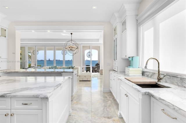 kitchen with white cabinetry, glass insert cabinets, light stone countertops, and a sink