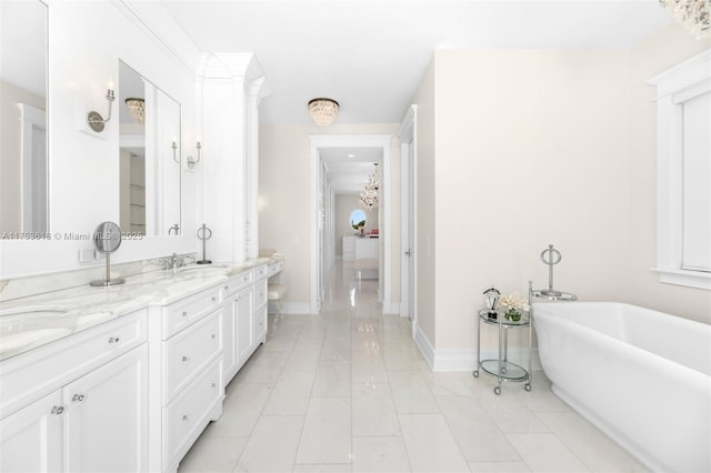 full bathroom featuring baseboards, double vanity, a freestanding tub, a sink, and tile patterned flooring