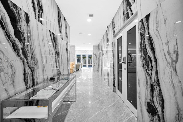 hallway with stone wall, visible vents, marble finish floor, and french doors