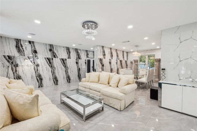 living area with recessed lighting, marble finish floor, and a notable chandelier
