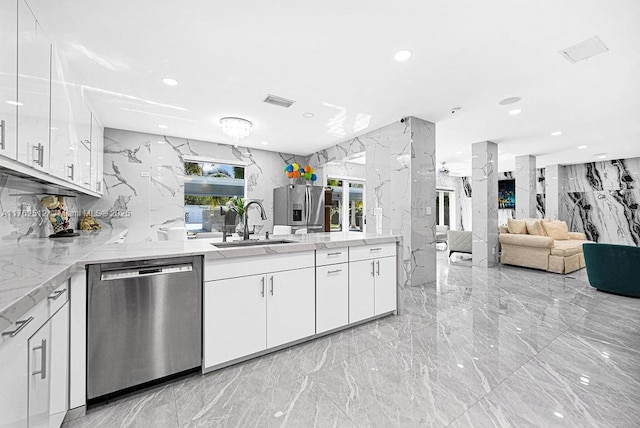 kitchen featuring stone wall, marble finish floor, appliances with stainless steel finishes, and a sink