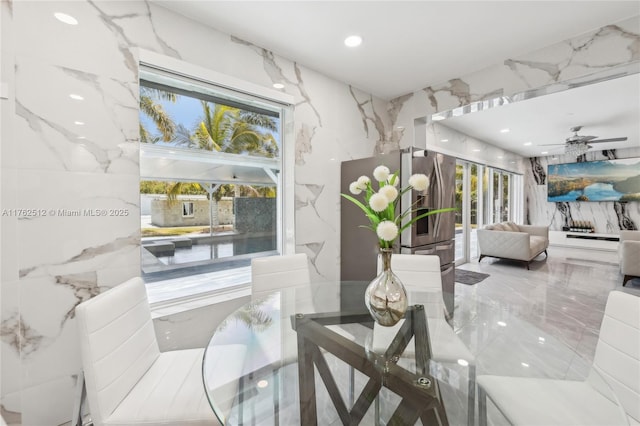 dining space featuring ceiling fan, recessed lighting, and stone wall