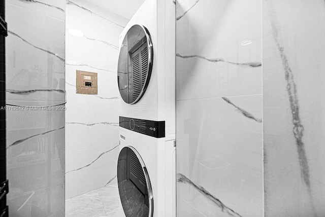 laundry room featuring stacked washer and dryer, marble finish floor, and laundry area