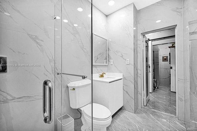 bathroom with vanity, stone wall, a stall shower, toilet, and marble finish floor