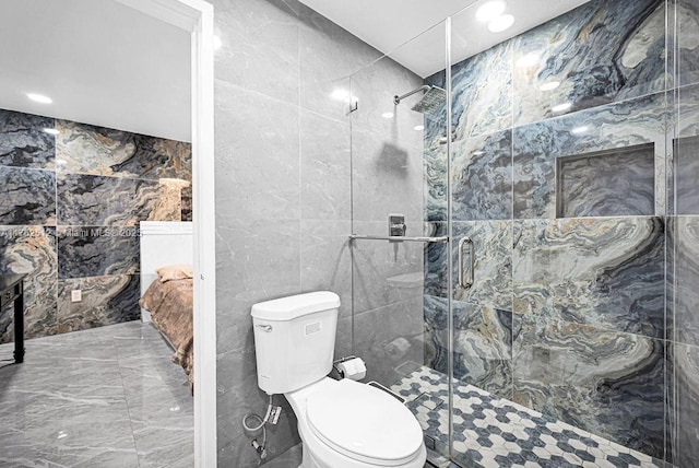 bathroom featuring toilet, a stall shower, tile walls, and marble finish floor