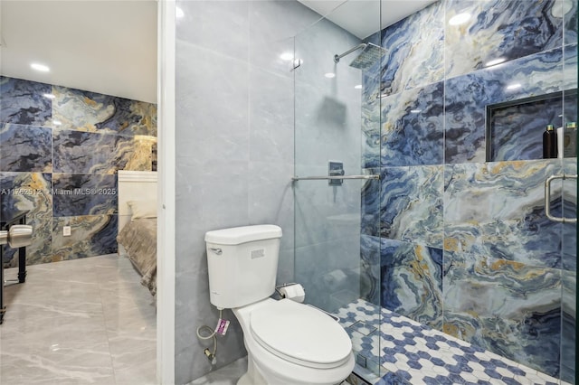 bathroom with toilet, tiled shower, and tile walls