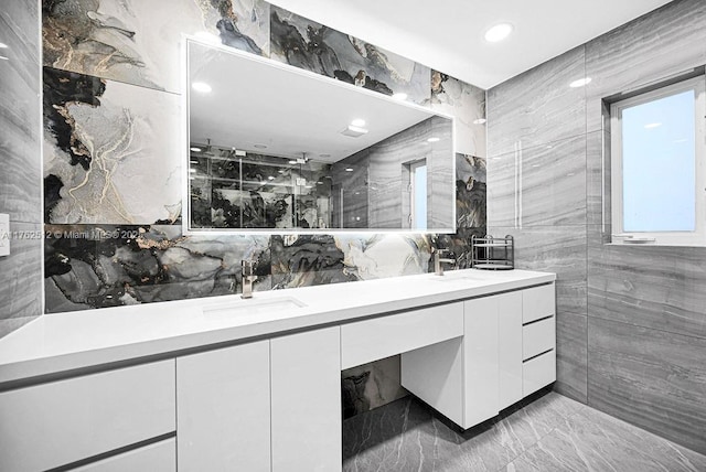 full bathroom featuring double vanity, tile walls, and a sink