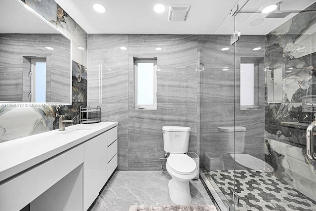 bathroom featuring vanity, a stall shower, tile walls, toilet, and marble finish floor