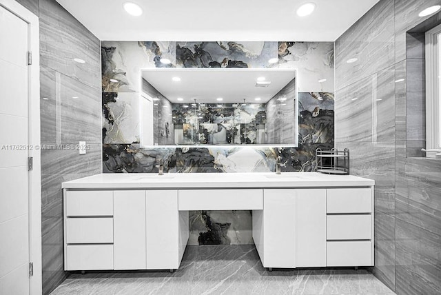 full bath featuring a sink, tile walls, and double vanity