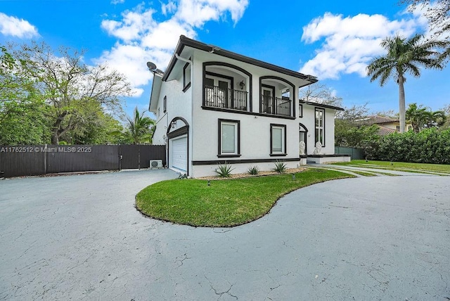 view of front facade featuring stucco siding, driveway, a balcony, and fence