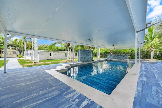 pool featuring a patio area, a storage shed, and an outdoor structure