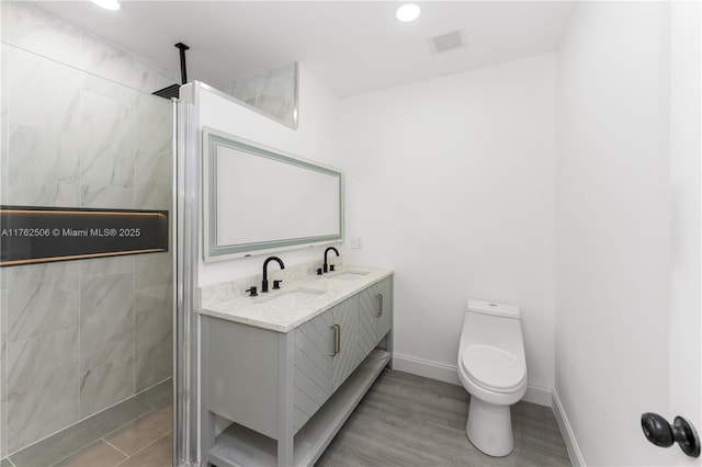 full bath with a sink, visible vents, and a tile shower