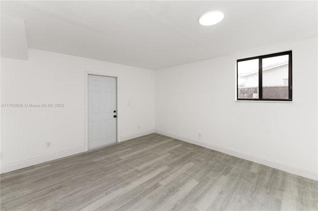 unfurnished room with baseboards and light wood-style floors