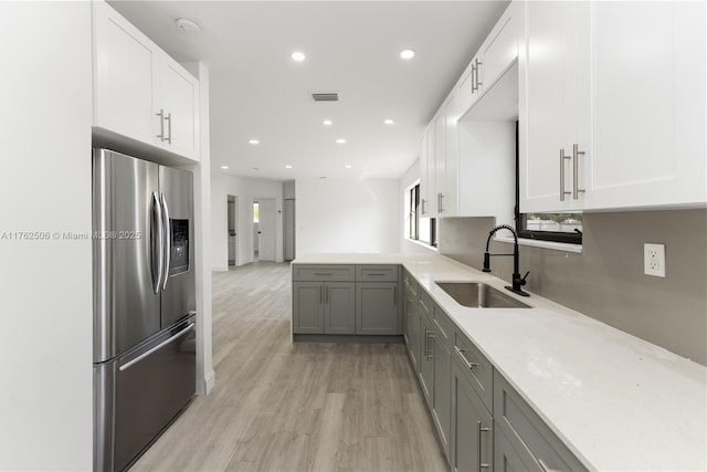 kitchen with visible vents, gray cabinetry, a sink, stainless steel fridge, and white cabinets