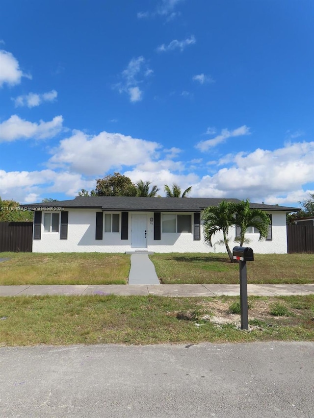 ranch-style home featuring stucco siding, a front yard, and fence