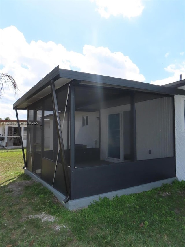 back of property featuring a lawn and a sunroom