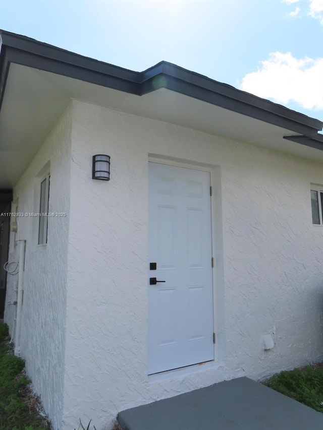 doorway to property featuring stucco siding