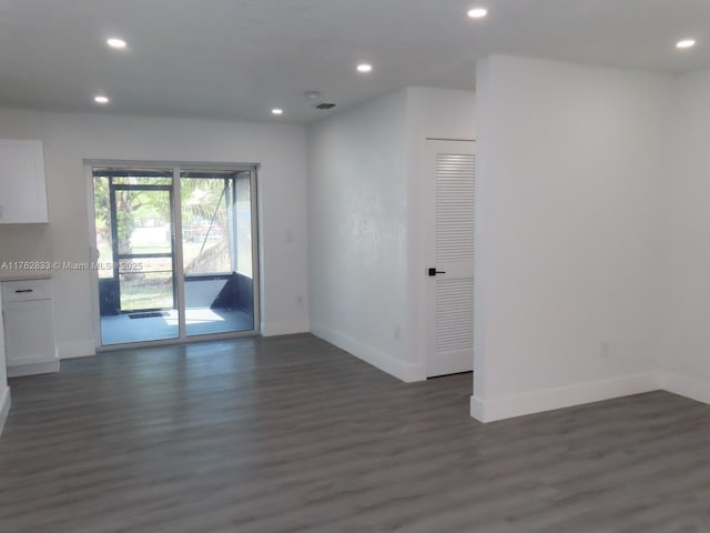 empty room with dark wood-style floors, recessed lighting, and baseboards