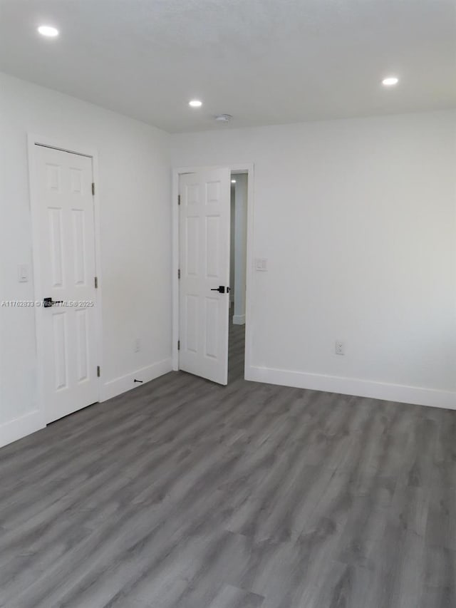 spare room with recessed lighting, dark wood-style floors, and baseboards