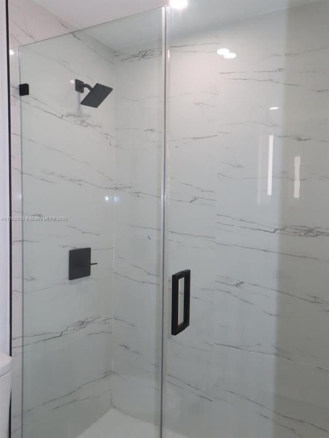 full bathroom with a marble finish shower and toilet