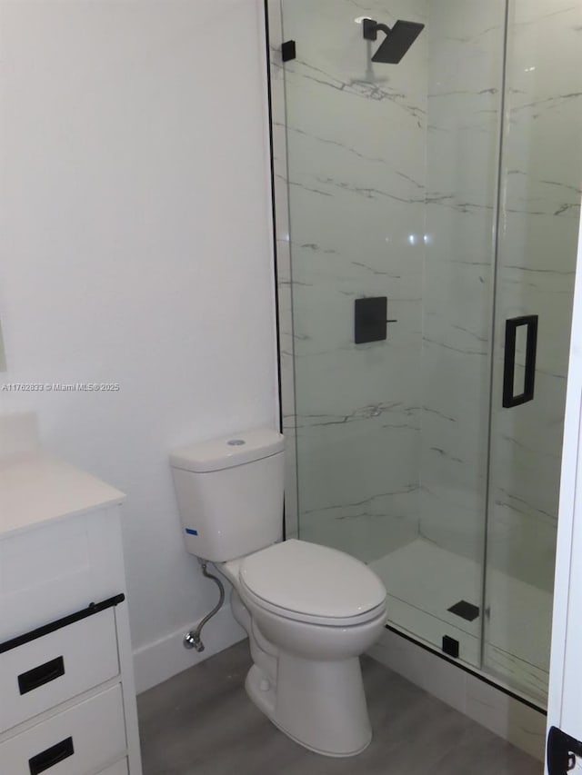 bathroom with a marble finish shower, toilet, and vanity