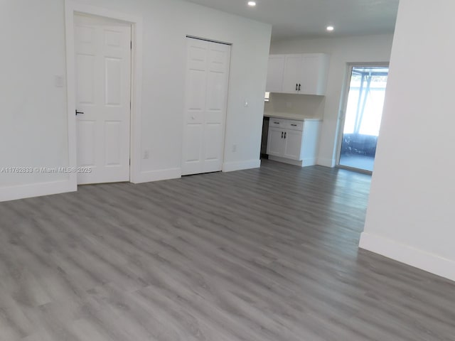 unfurnished living room featuring recessed lighting, wood finished floors, and baseboards