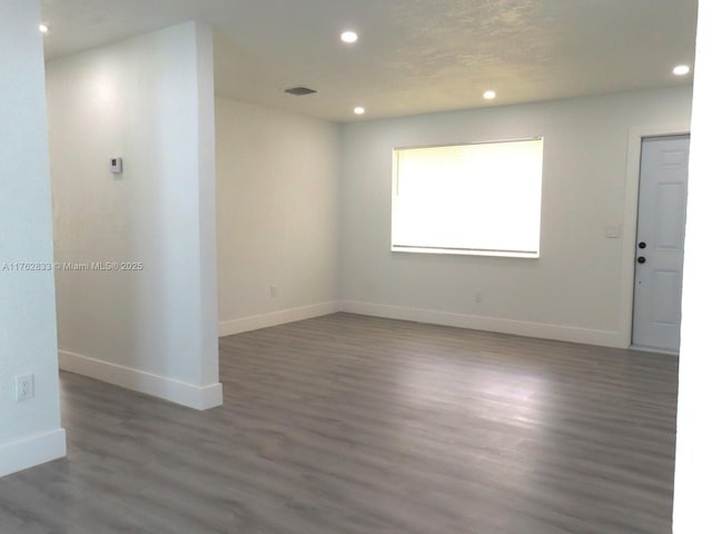 spare room with recessed lighting, visible vents, baseboards, and wood finished floors