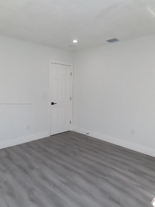 spare room featuring dark wood finished floors, visible vents, recessed lighting, and baseboards