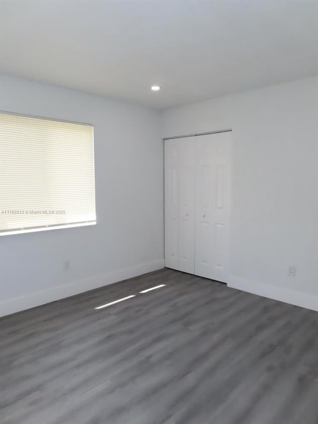 unfurnished bedroom with recessed lighting, a closet, baseboards, and wood finished floors