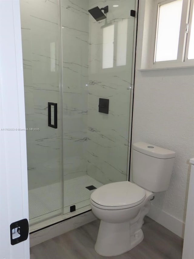 bathroom featuring a marble finish shower, baseboards, toilet, and wood finished floors