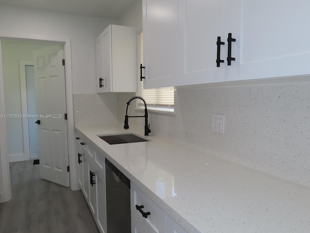 kitchen featuring a sink, light stone countertops, wood finished floors, white cabinets, and stainless steel dishwasher