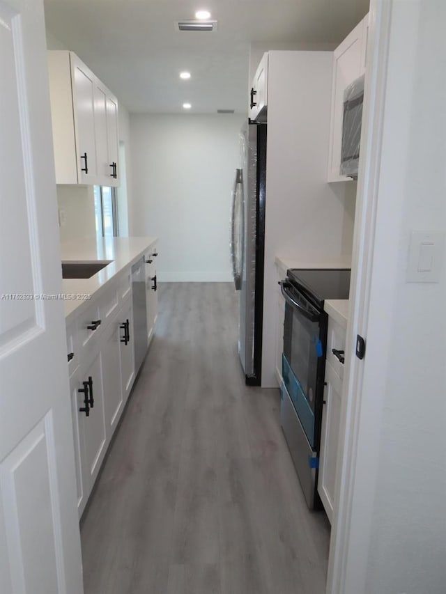 kitchen with visible vents, light wood finished floors, white cabinetry, appliances with stainless steel finishes, and light countertops