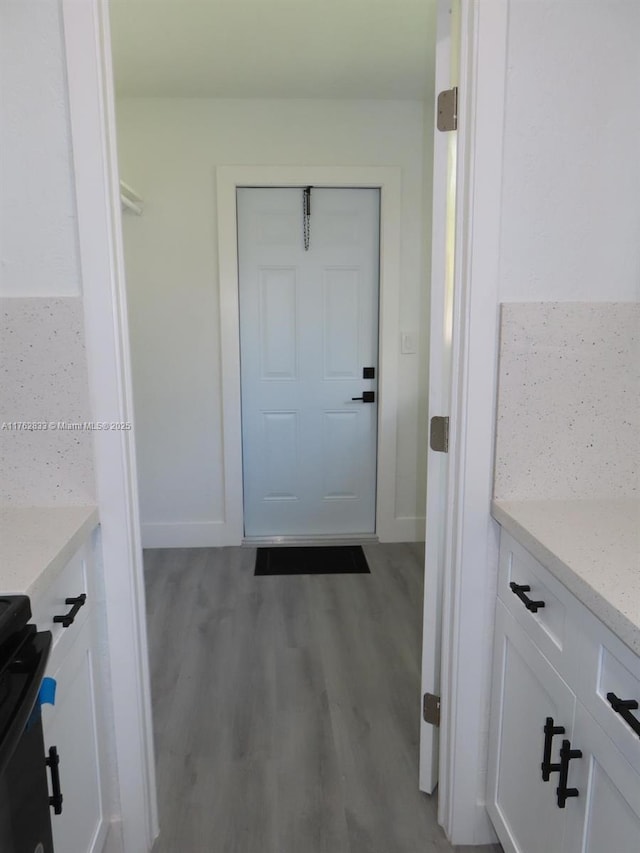 doorway featuring baseboards and wood finished floors