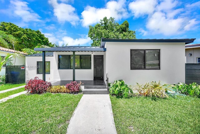 2261 SW 26th St, Miami, FL 33133 - view of front of home with a front lawn, stucco siding, and covered porch