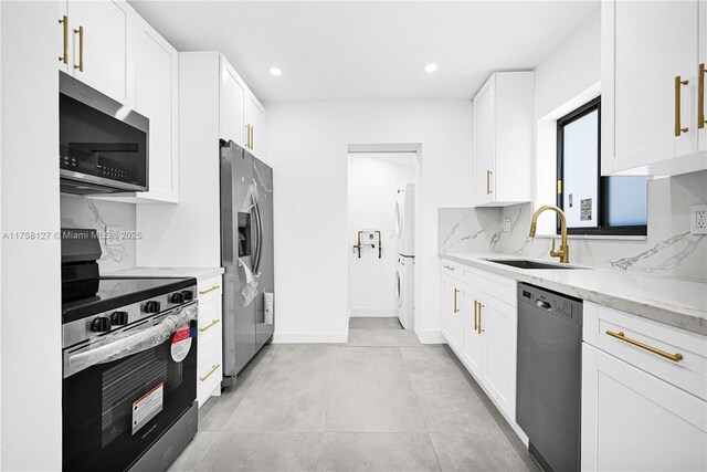 2261 SW 26th St, Miami, FL 33133 - kitchen with appliances with stainless steel finishes, a sink, stacked washer / dryer, tasteful backsplash, and light stone countertops