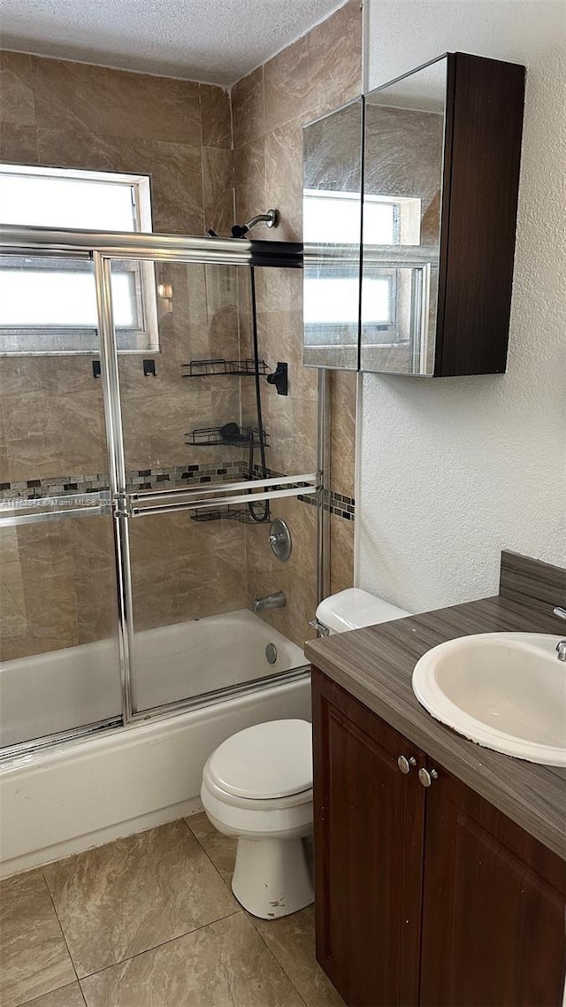 full bath with toilet, a textured ceiling, enclosed tub / shower combo, vanity, and a textured wall