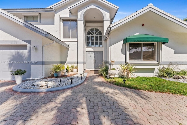 property entrance with a garage and stucco siding