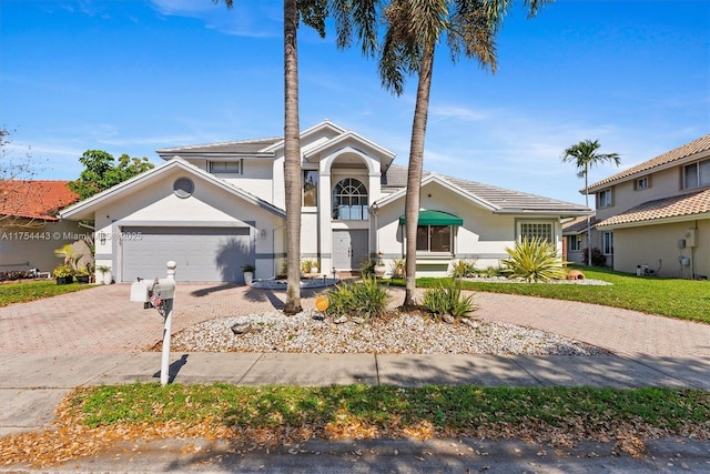 view of front of home with a front lawn, decorative driveway, an attached garage, and stucco siding