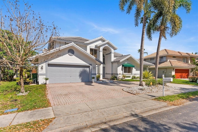 view of front of home featuring decorative driveway, a garage, and stucco siding