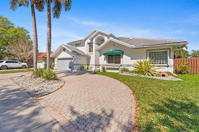 view of front of property featuring stucco siding, a front lawn, decorative driveway, fence, and an attached garage